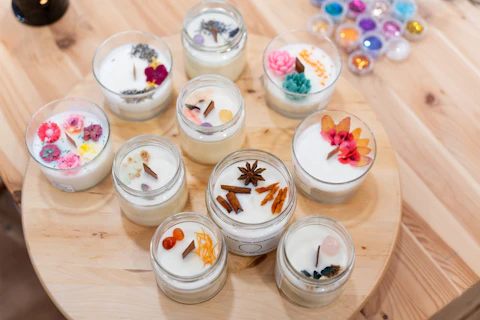 Variety of natural soy candles prepared during a workshop, decorated with dried flowers, herbs, and spices