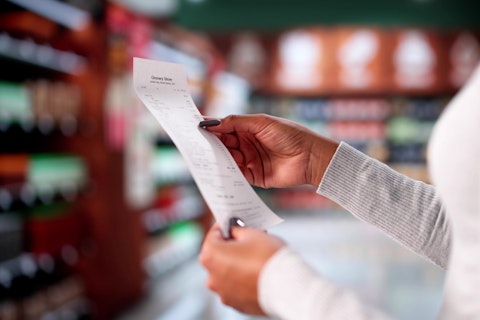 Woman Checking Grocery Store Receipt After Shopping At Supermarket