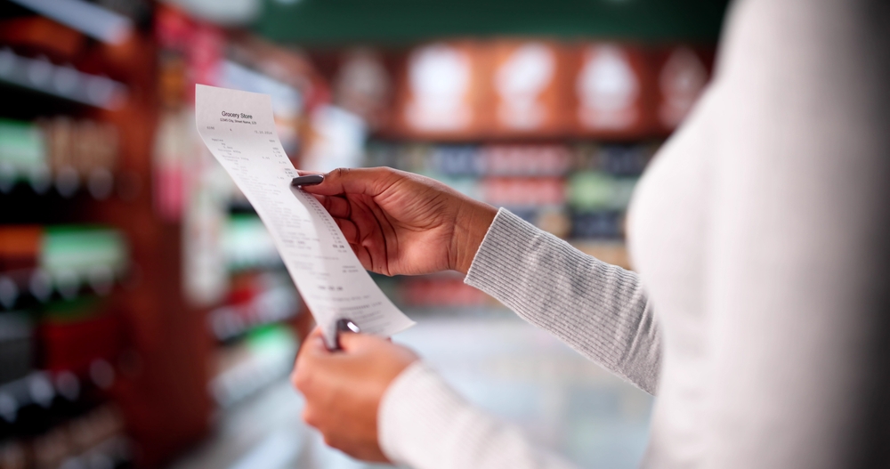 Woman Checking Grocery Store Receipt After Shopping At Supermarket