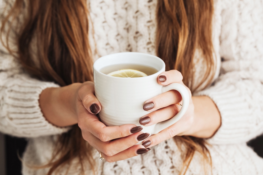 Woman holding mug of lemon tea
