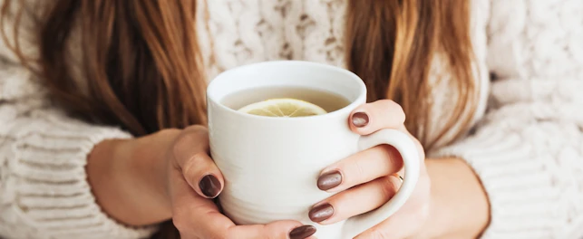 Woman holding mug of lemon tea
