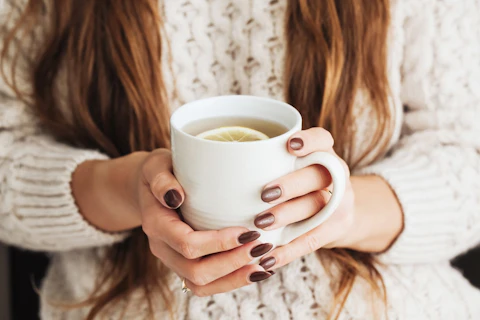 Woman holding mug of lemon tea