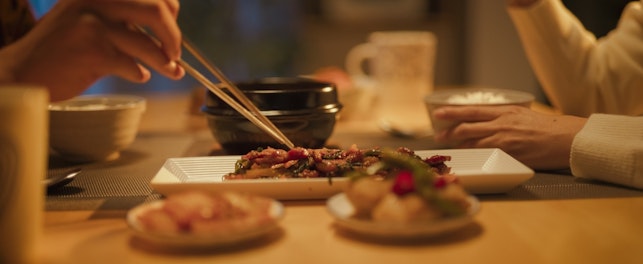 Women Using Chopstick on the Food at the Table