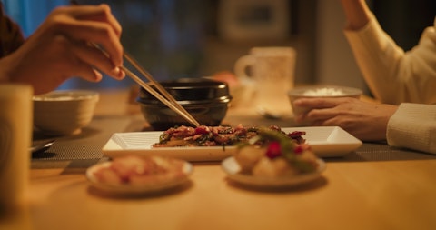 Women Using Chopstick on the Food at the Table