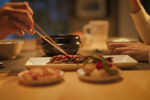 Women Using Chopstick on the Food at the Table