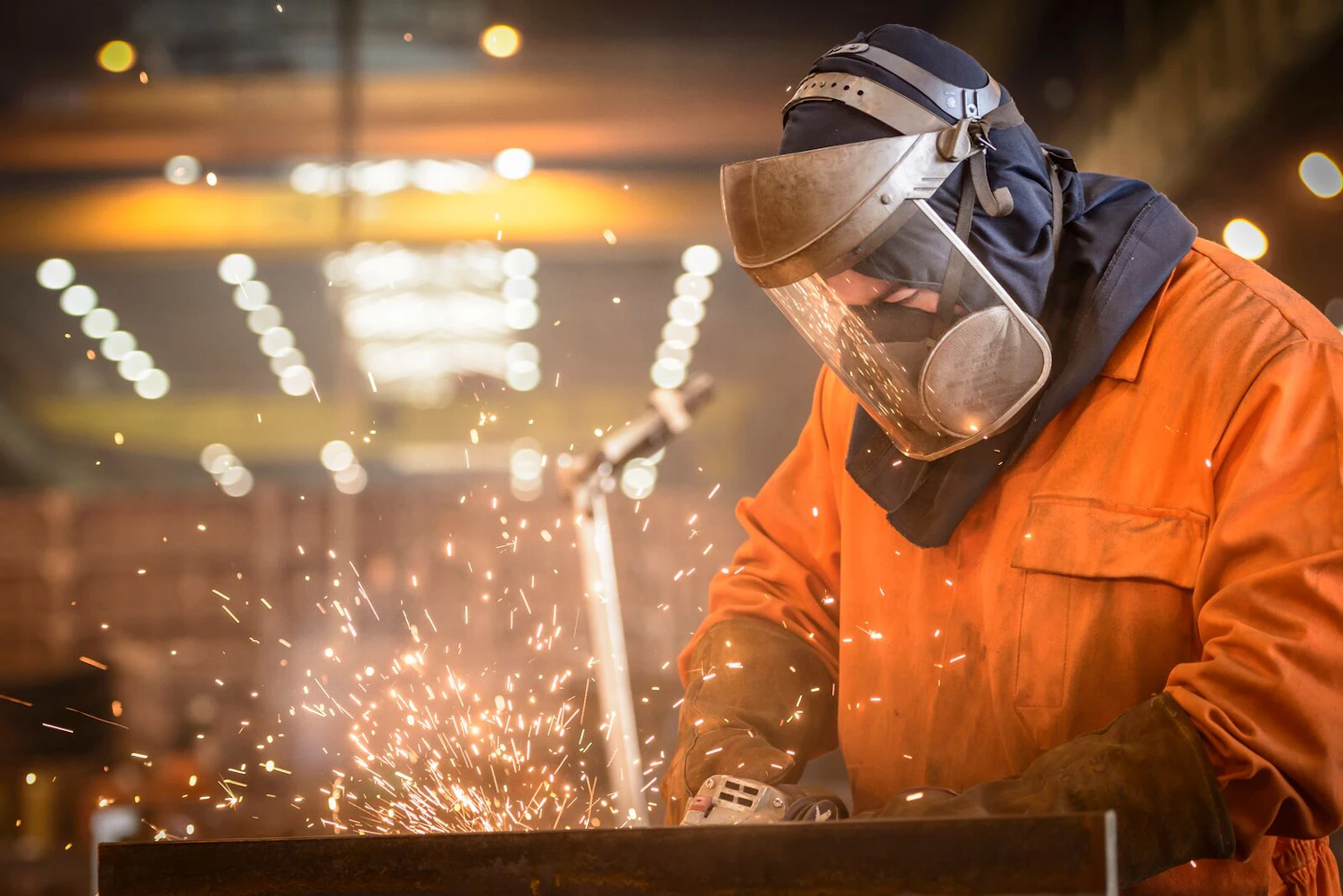 Worker Grinding Metal in Factory