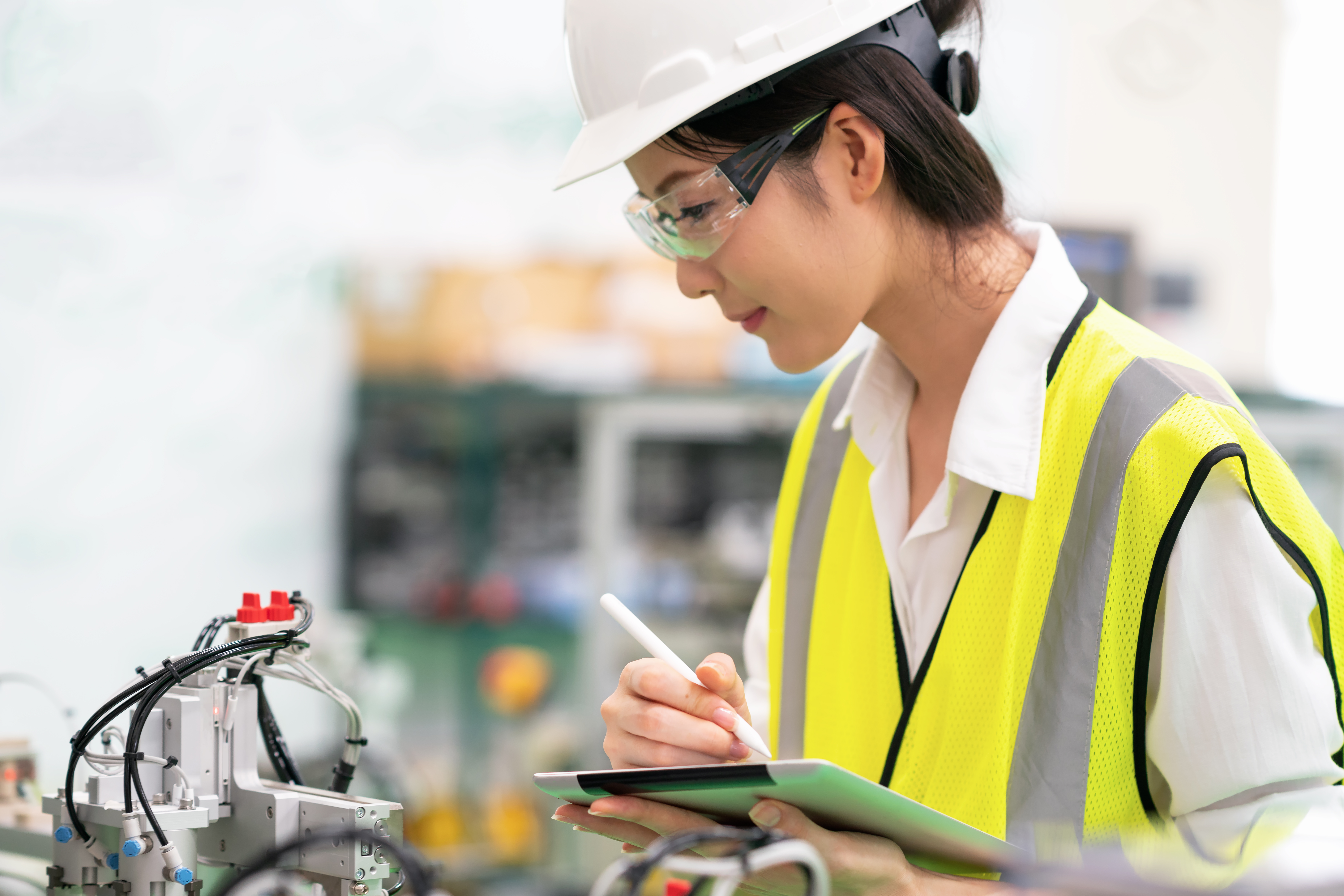 Woman Using Digital Tablet Controlling Machine in a Factory