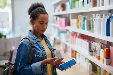 African American reading labels on skin care products while shopping in a pharmacy