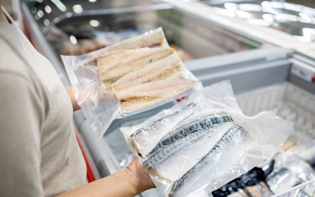 Asian Woman Wear Face Mask Choosing Packed Frozen Cut Fish in Freezer