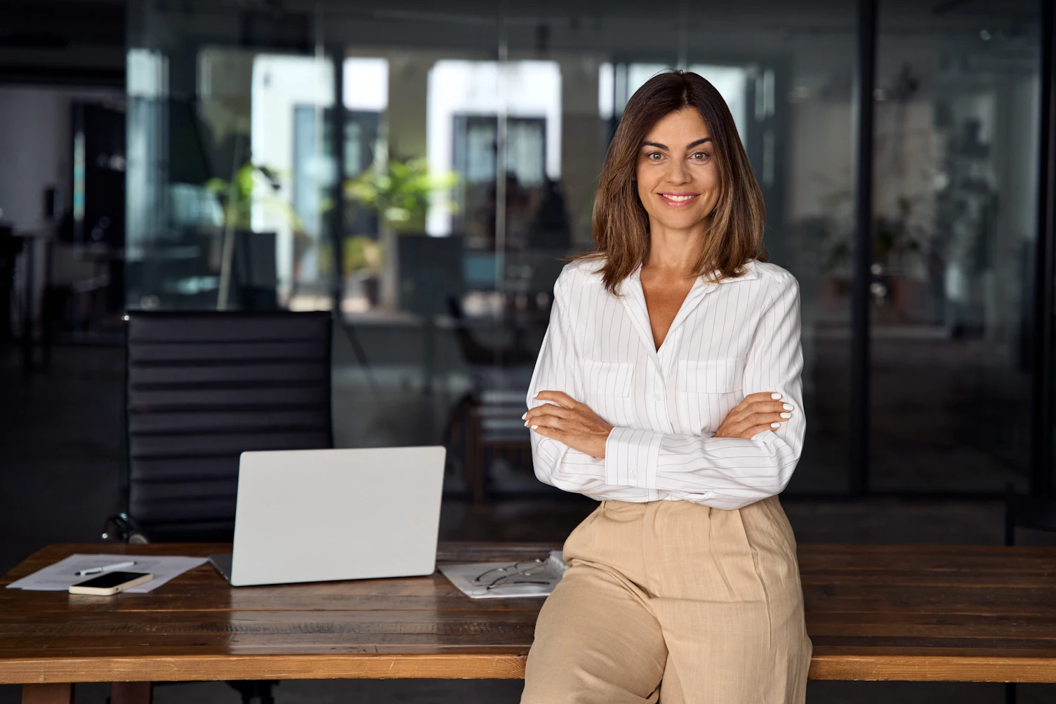 Beautiful hispanic senior business woman with crossed arms smiling at camera