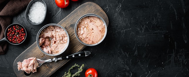 Canned italian tuna set on wooden cutting board