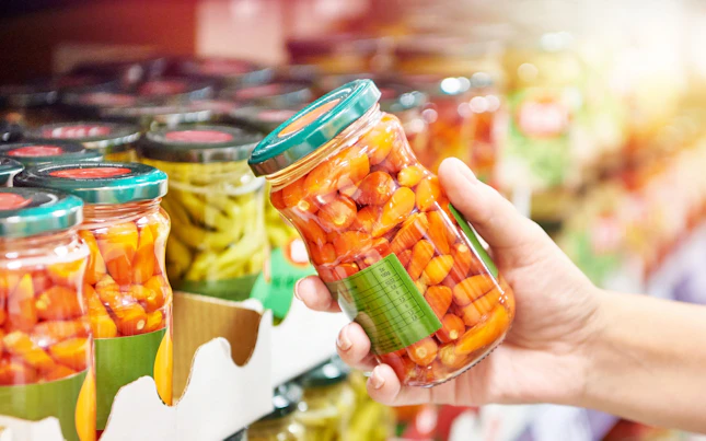 Canned red peppers vegetables in hands in store