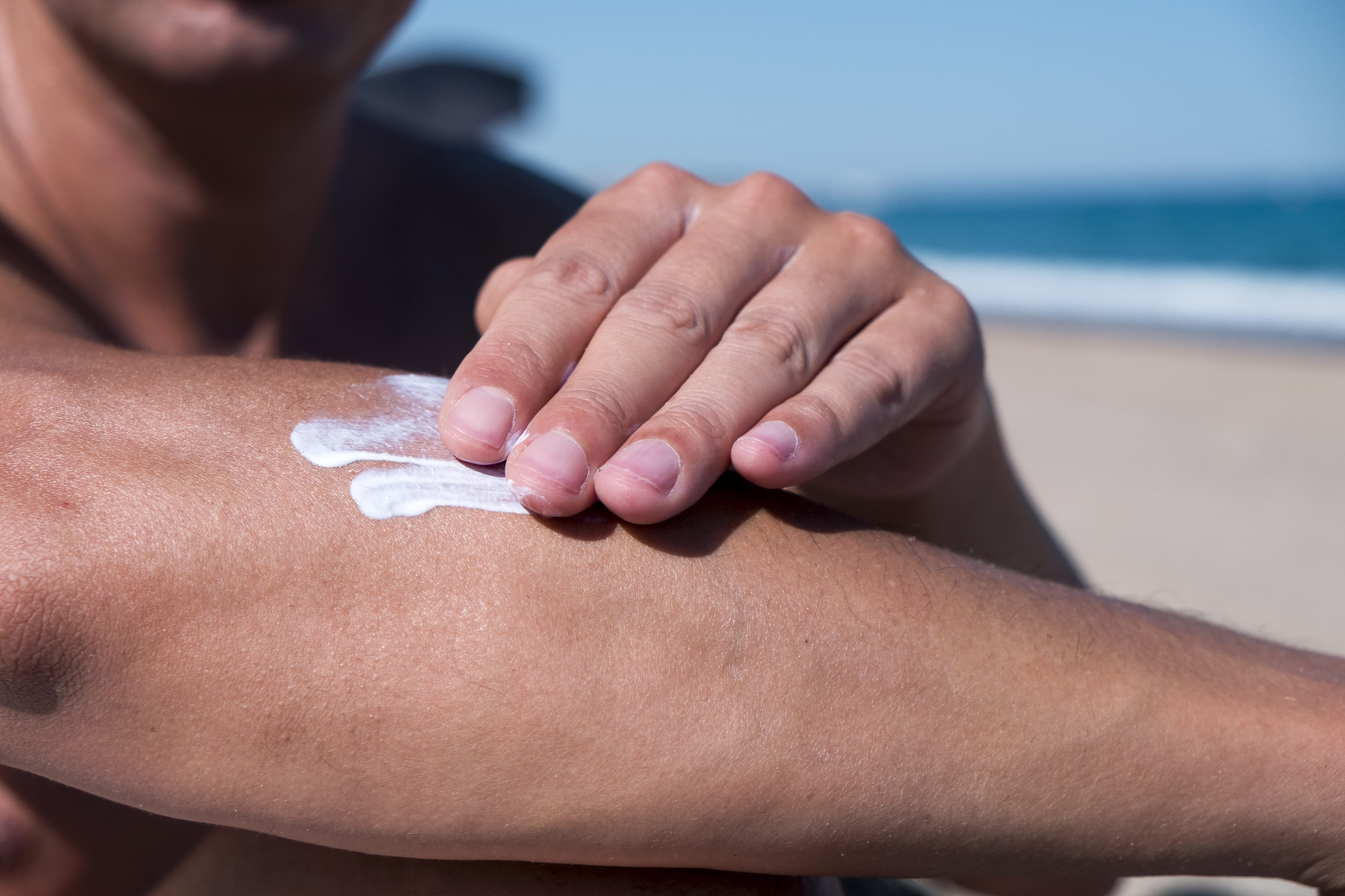 Closeup of a Man on the Beach Applying Sunscreen