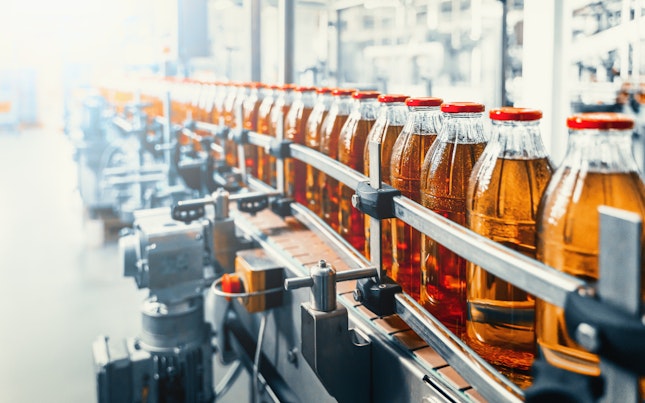 Conveyor belt juice in glass bottles on beverage plant or factory interior industrial manufacturing