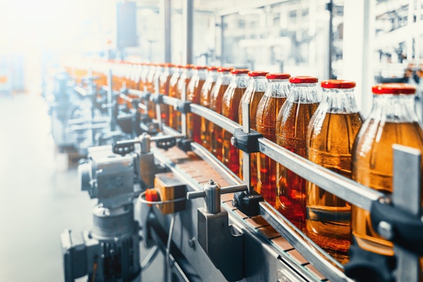 Conveyor belt juice in glass bottles on beverage plant or factory interior industrial manufacturing