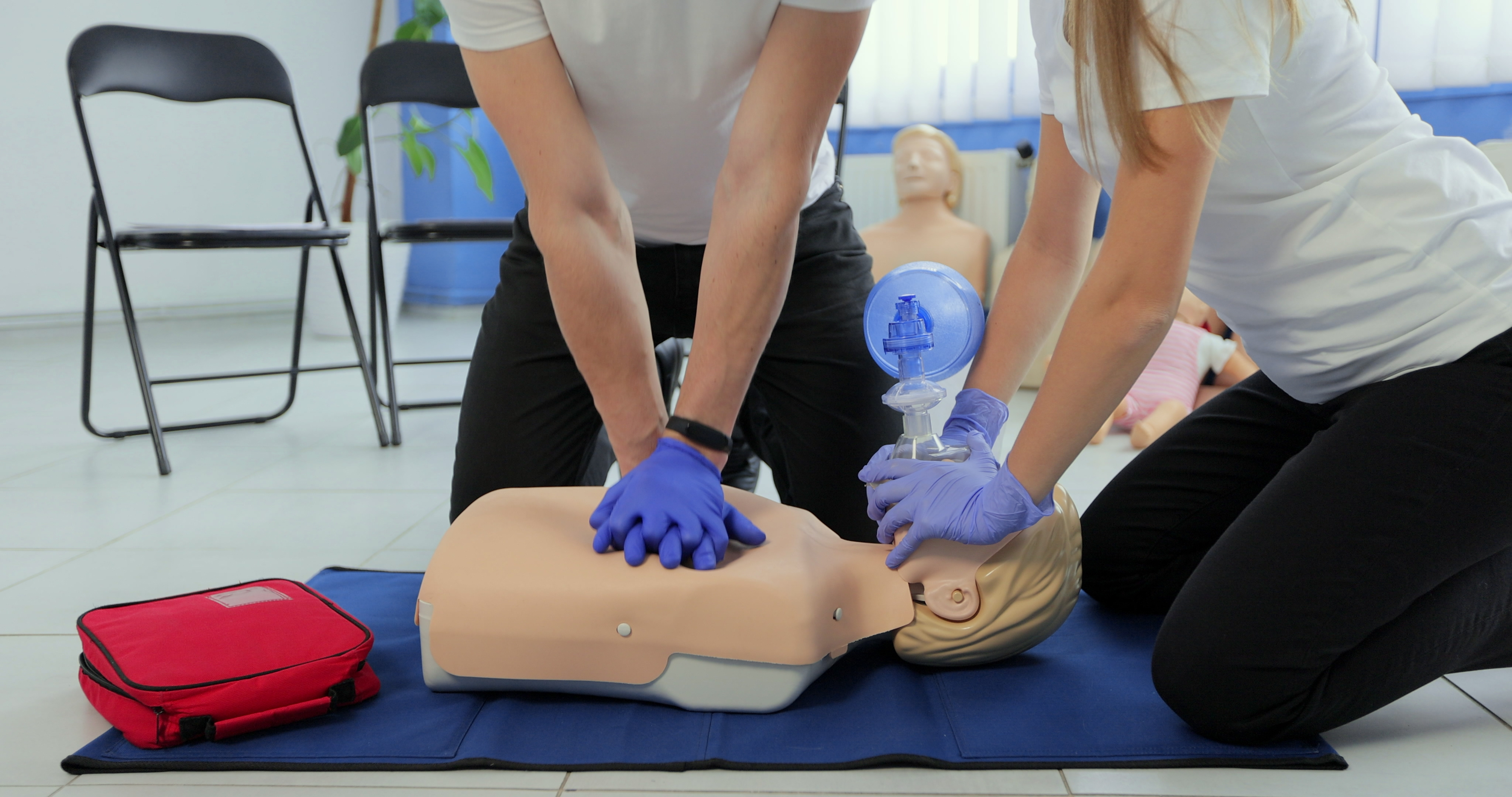CPR classes students practicing in a dummy with rubber gloves