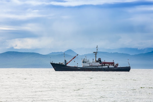 Fishing Vessel on the Background of Hills and Volcanoes