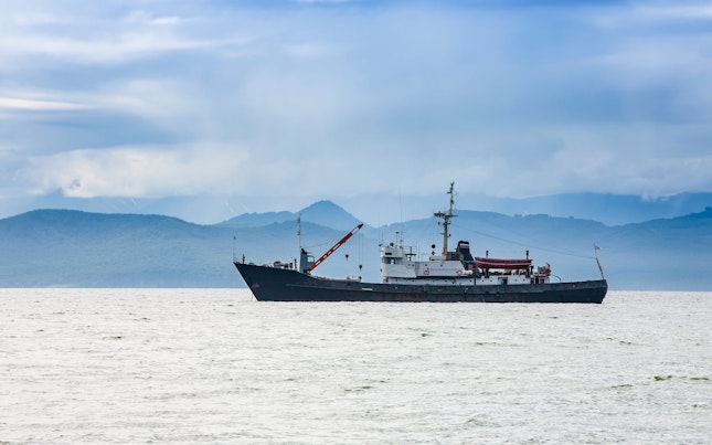 Fishing Vessel on the Background of Hills and Volcanoes