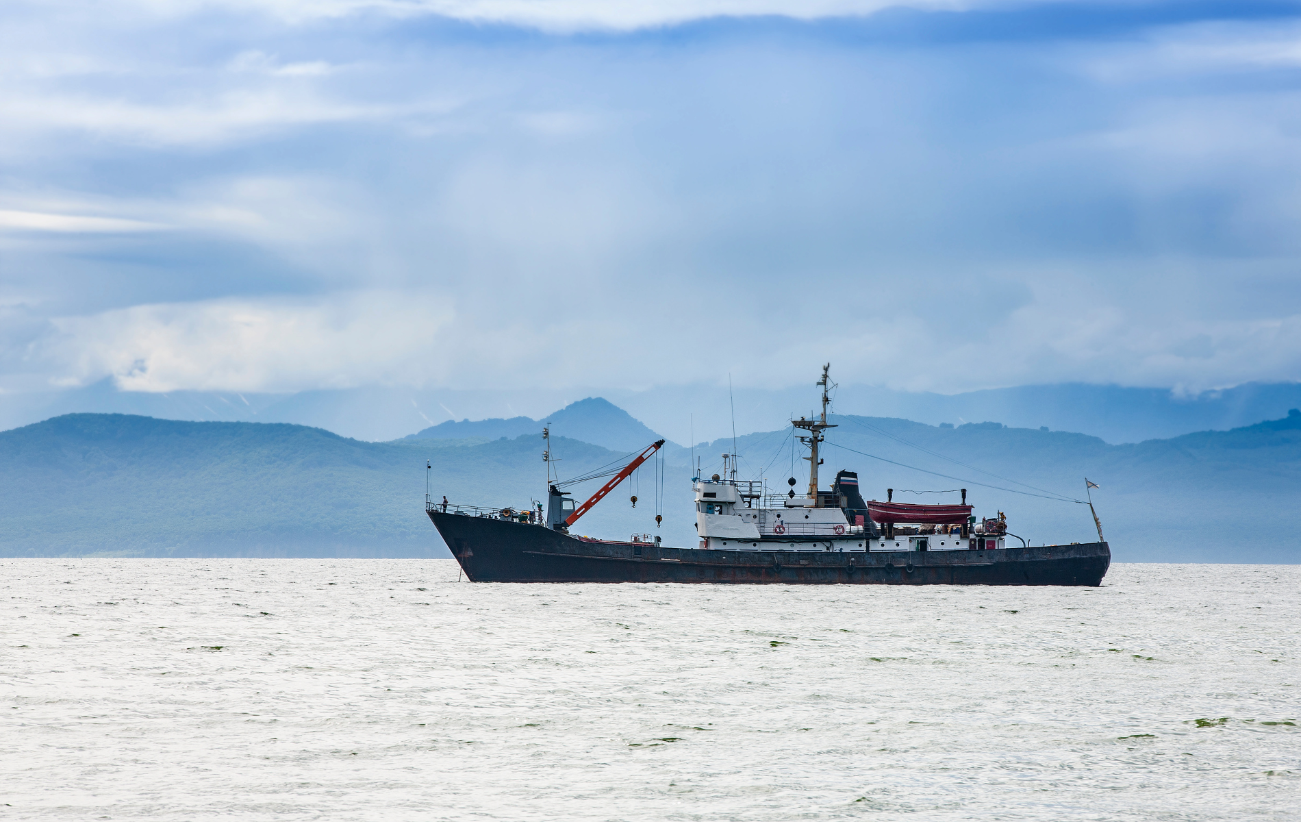Fishing Vessel on Water with Mountainous Background