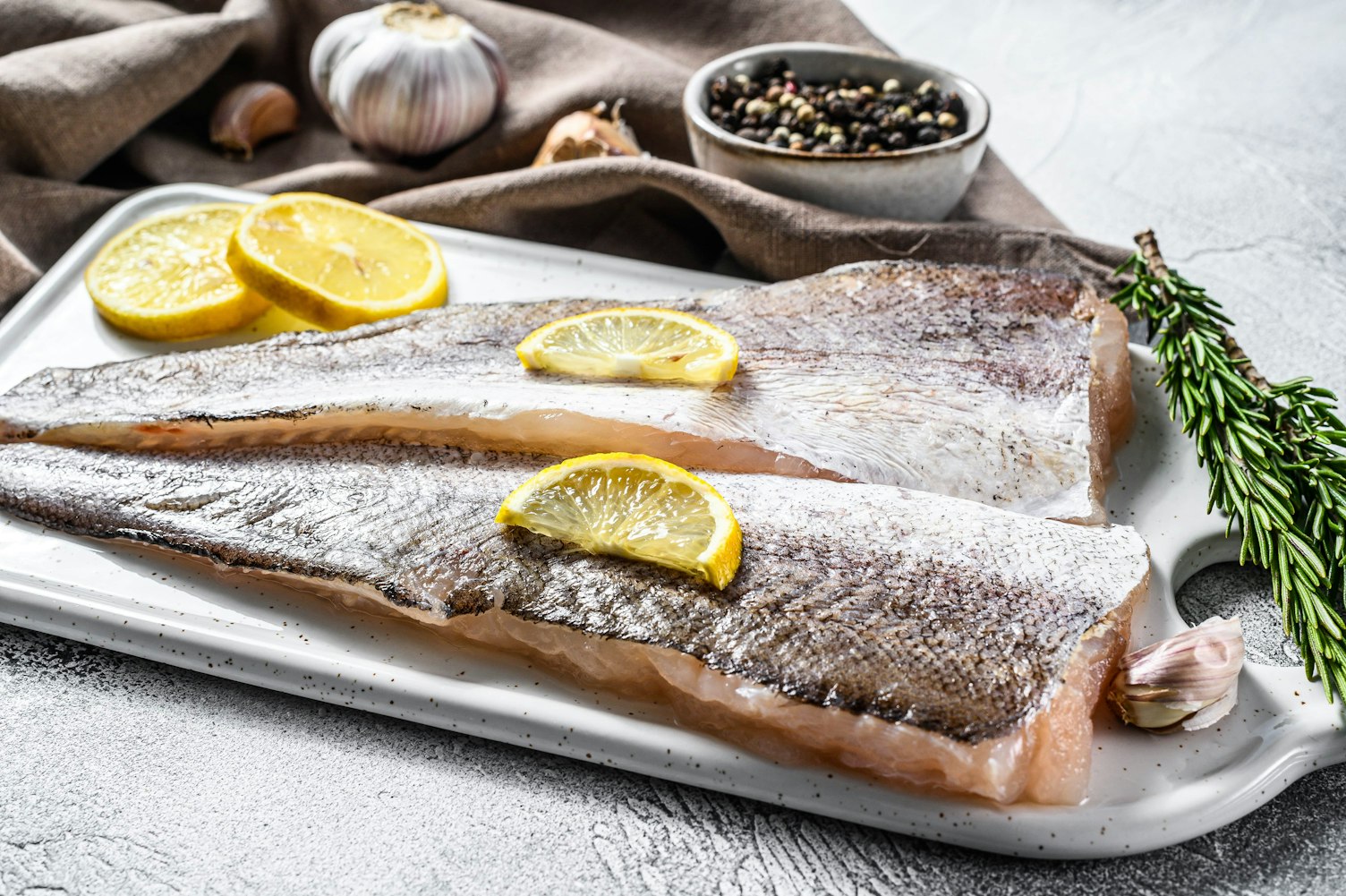 Fresh raw hake fish fillet with pepper and lemon