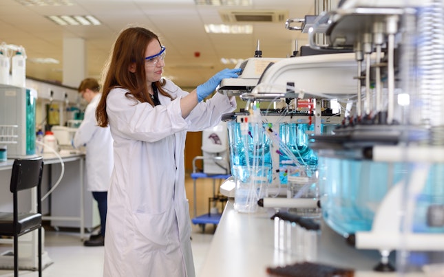 Female looking in a microscope in a lab