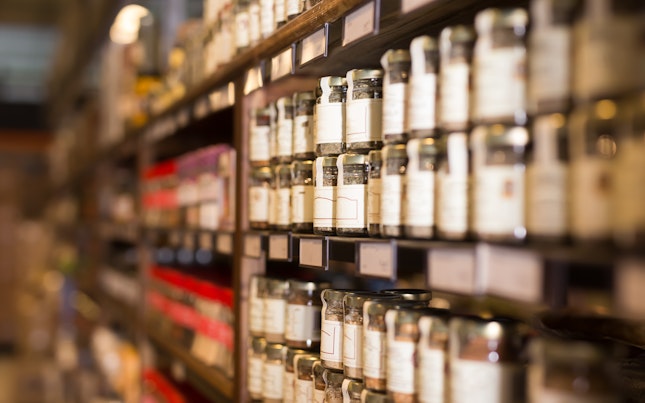 Large assortment of natural seasonings and spices in glass jars on store counter