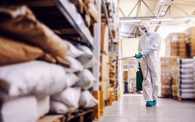 Man in Protective Suit Disinfecting Warehouse