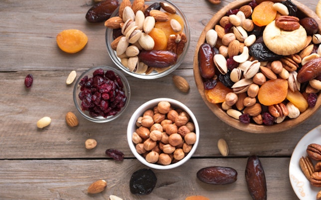 Mixed nuts and dried fruits in wooden bowl on wooden background, top view, banner. Healthy snack - mix of organic nuts and dry fruits