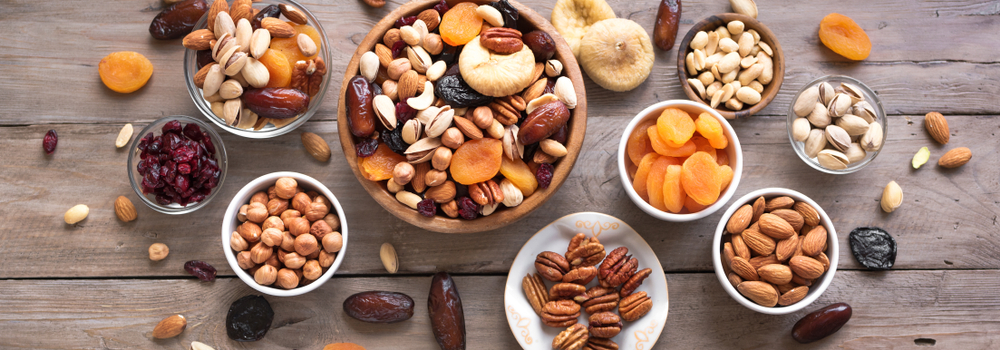 Mixed nuts and dried fruits in wooden bowl on wooden background, top view, banner. Healthy snack - mix of organic nuts and dry fruits