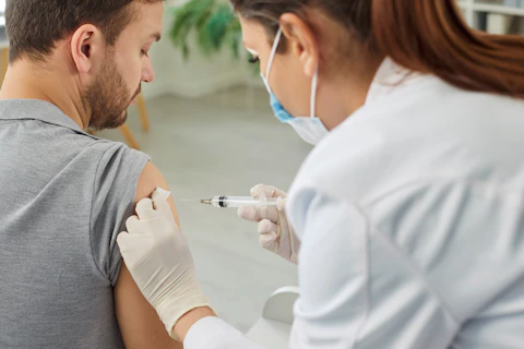 Nurse or Doctor Giving Injection in the Shoulder to Male Patient