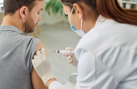 Nurse or Doctor Giving Injection in the Shoulder to Male Patient