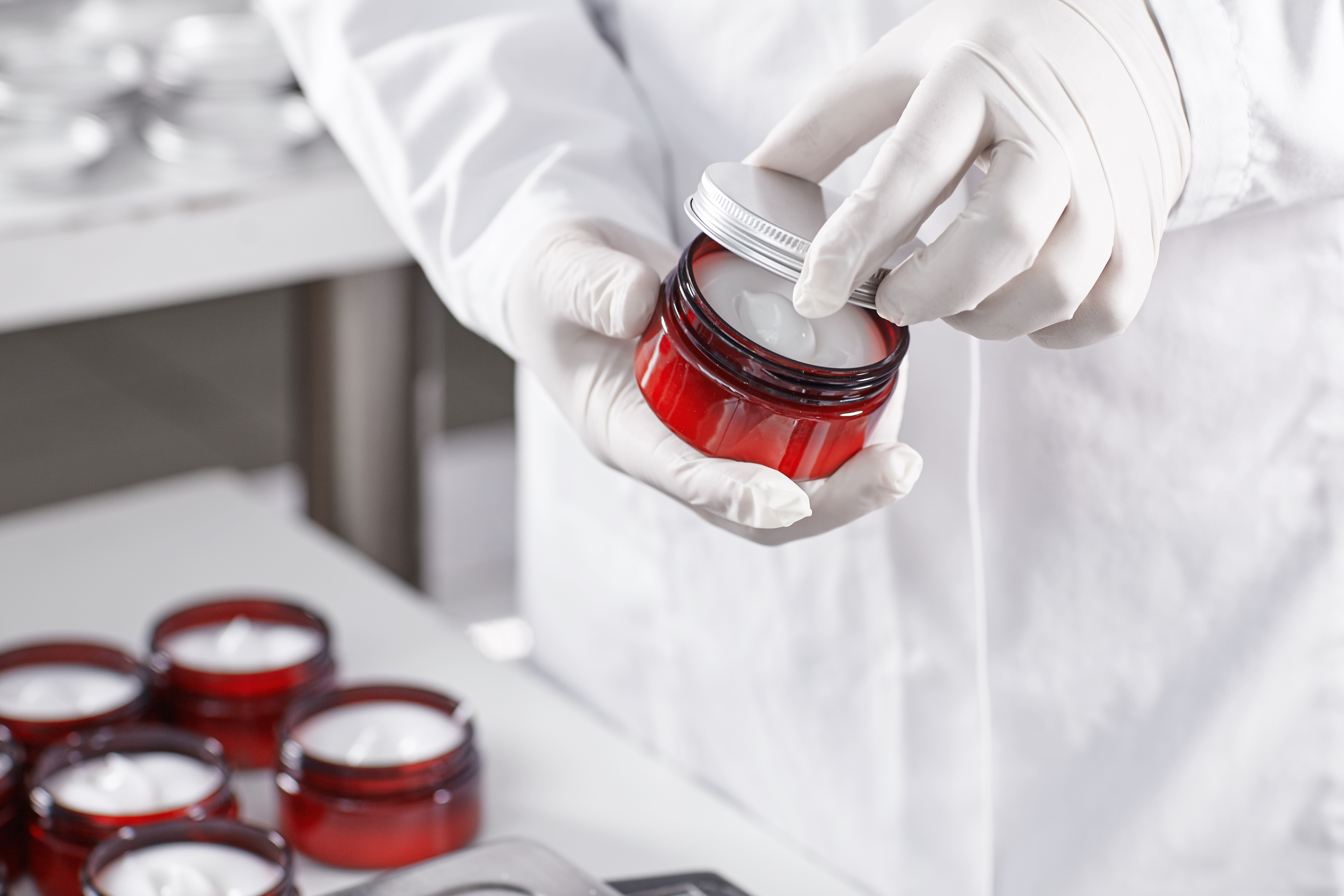 Lab technician holding a red container filled with skin care product