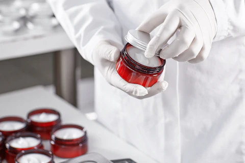 Lab technician holding a red container filled with skin care product