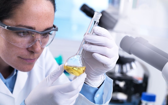 Scienziato che usa un matraccio per miscelare sostanze chimiche