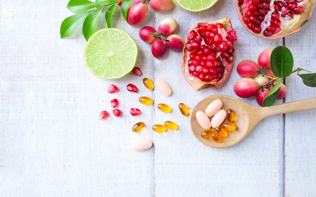 Vitamin Supplements on Wooden Spoon with Healthy Fruits