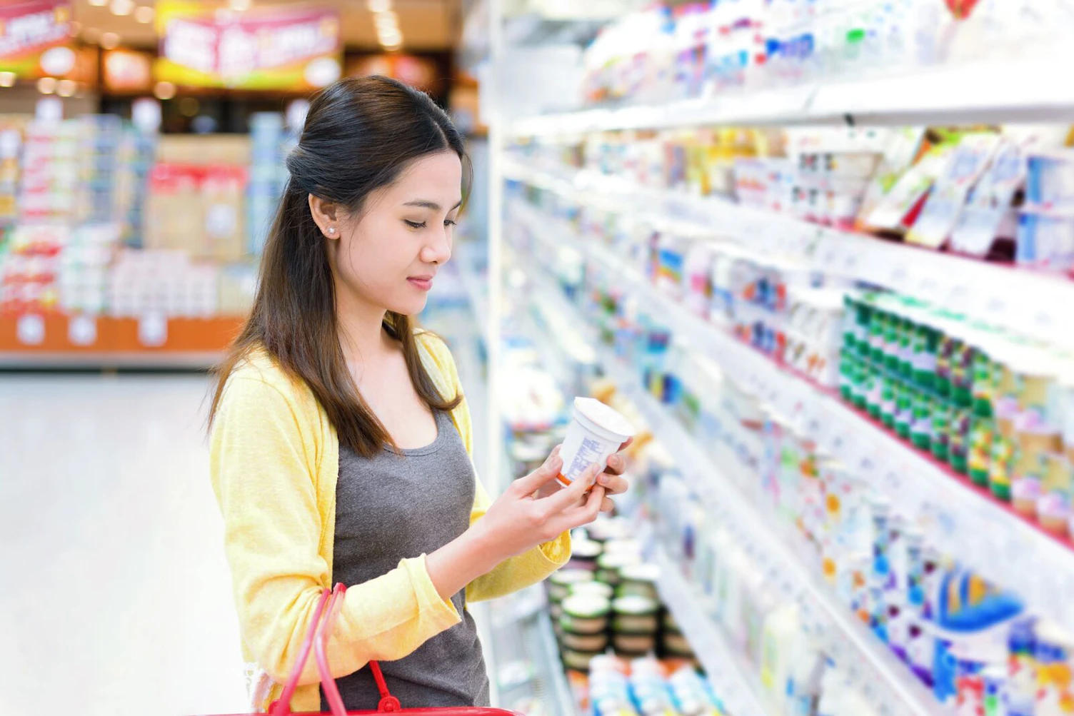Mulher a comprar um produto lácteo num supermercado