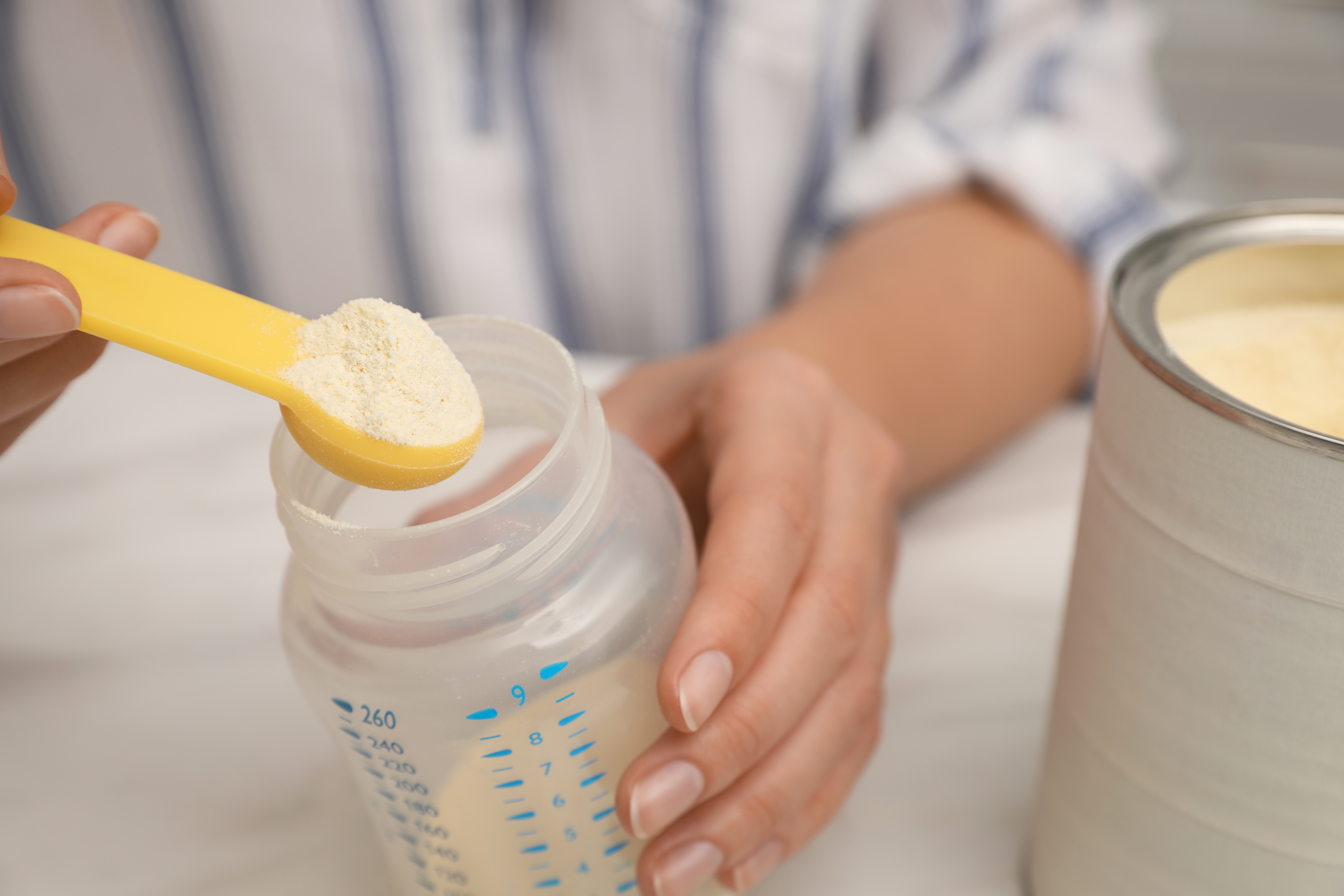 Woman preparing infant formula at table closeup Baby milk