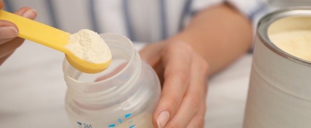 Woman preparing infant formula at table closeup Baby milk