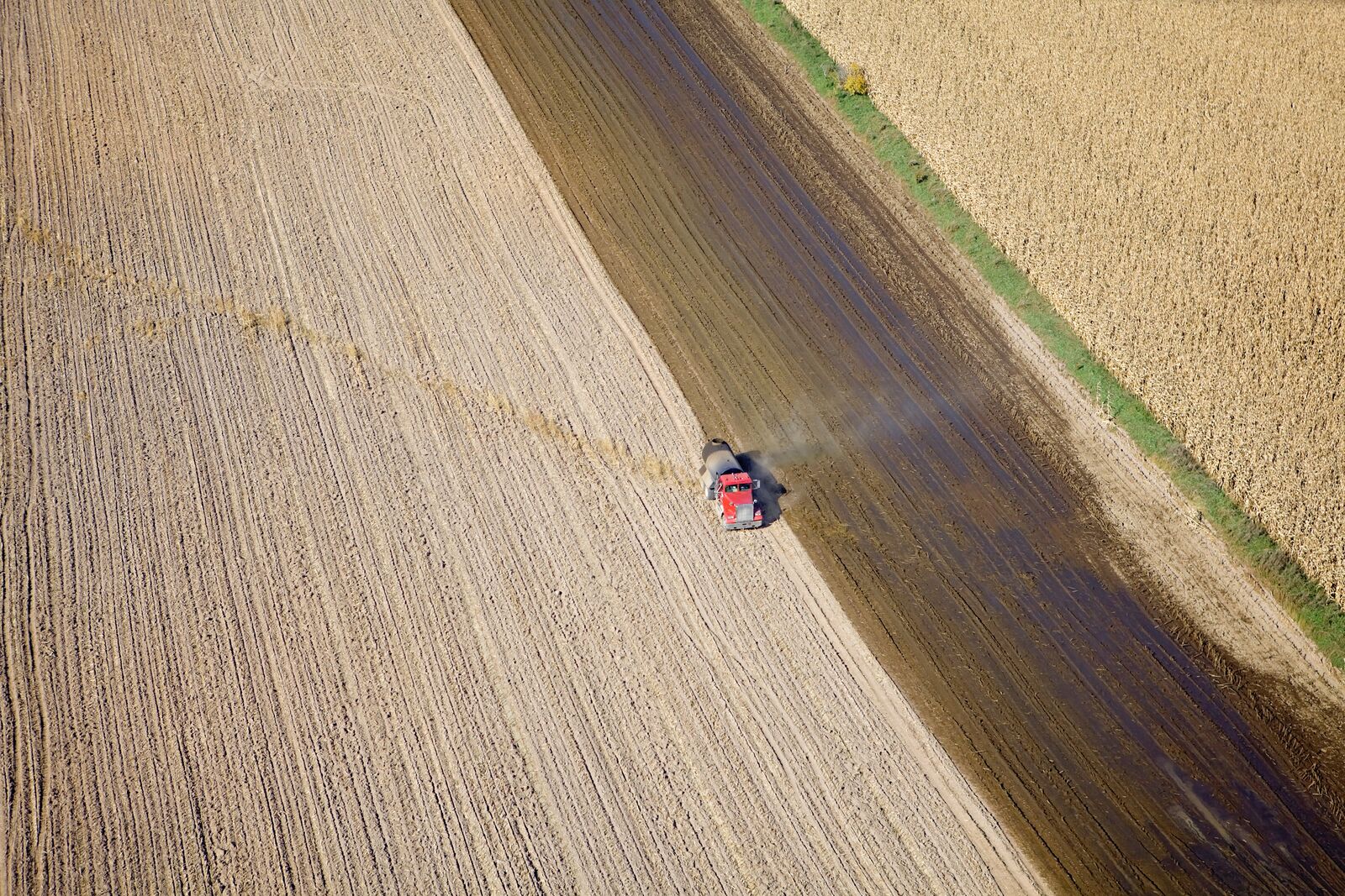 Aerial view of a tank truck spreading manure on a recently harvested corn field