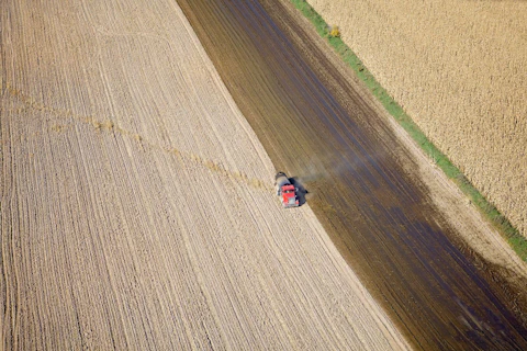 Aerial view of a tank truck spreading manure on a recently harvested corn field