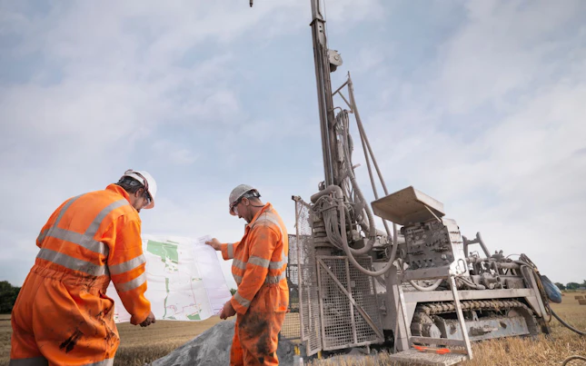 Drilling Rig Workers Inspecting Map in a Field