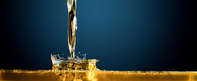 Scientifique en laboratoire analysant un liquide jaune dans un erlenmeyer, entourée de tubes à essai et d'un microscope.