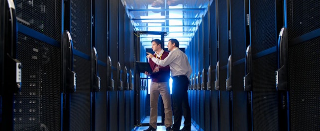 Manager and Technician with Laptop Talking in Aisle of Server Room