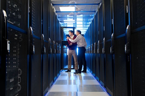 Manager and Technician with Laptop Talking in Aisle of Server Room