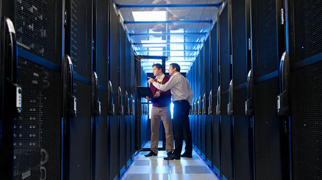 Manager and Technician with Laptop Talking in Aisle of Server Room Manager and Technician with Laptop Talking in Aisle of Server Room