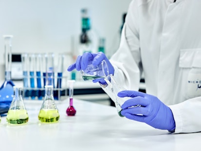 Manipulation chimique en laboratoire chez MICROLAB Scientifique en laboratoire effectuant une manipulation chimique avec des gants et des instruments de verrerie.