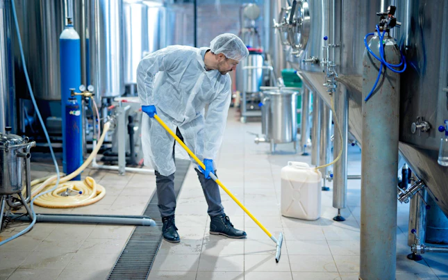 Professional Industrial Cleaner in Protective Uniform Cleaning Floor of Food Processing Plant