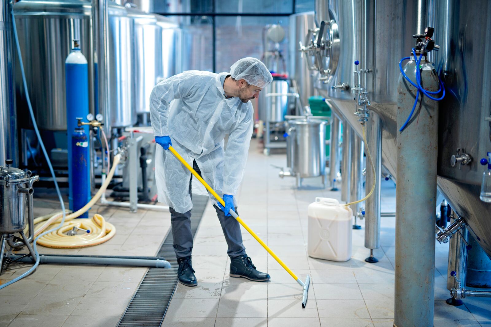 Professional Industrial Cleaner in Protective Uniform Cleaning Floor of Food Processing Plant