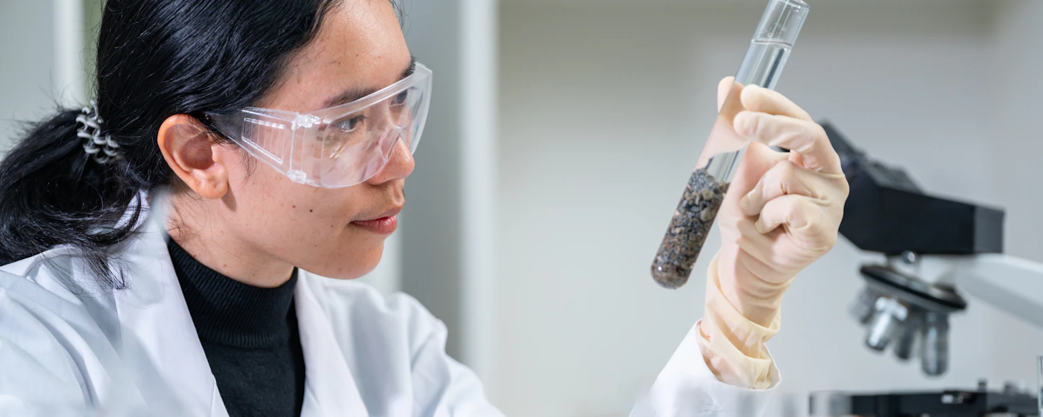 Onderzoeker, geoloog of archeoloog die in het veld of laboratorium werkt met een reageerbuisje met een monster van grond, gesteente of fossielen, en zich bezighoudt met studie en ontdekkingen op het gebied van paleontologie, archeologie en geologie.