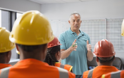 Formateur en train de donner une présentation à des ouvriers portant des casques de sécurité.